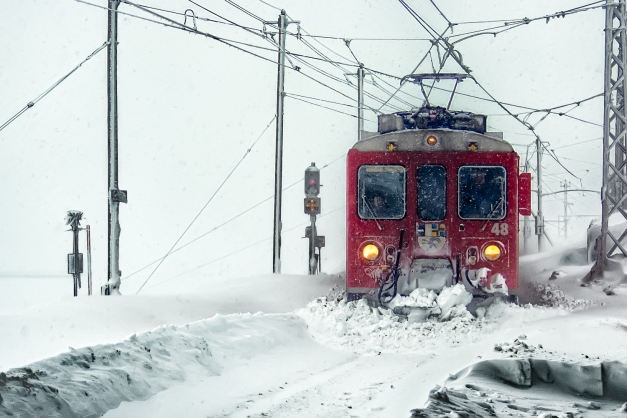 Train approaching Ospizio Bernina station in the snow